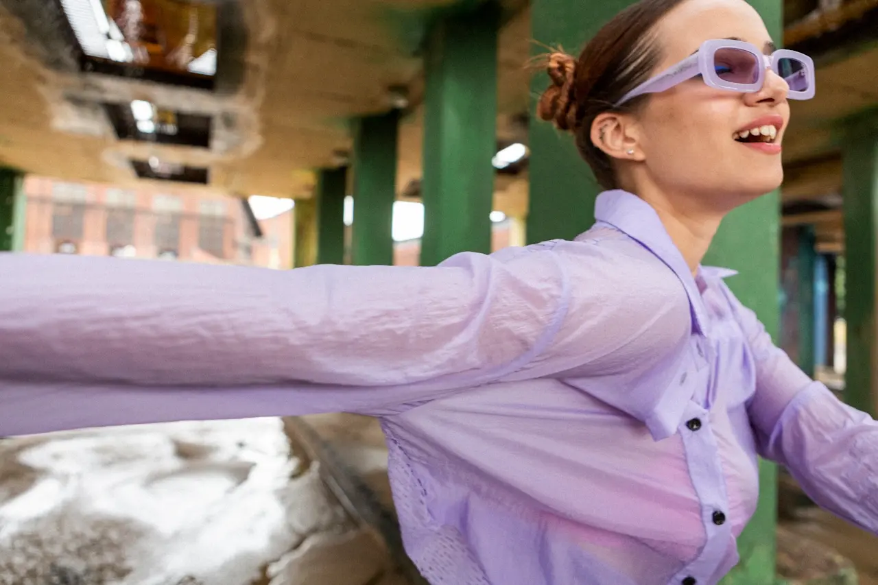 Young woman smiling in a purple shirt and sunglasses