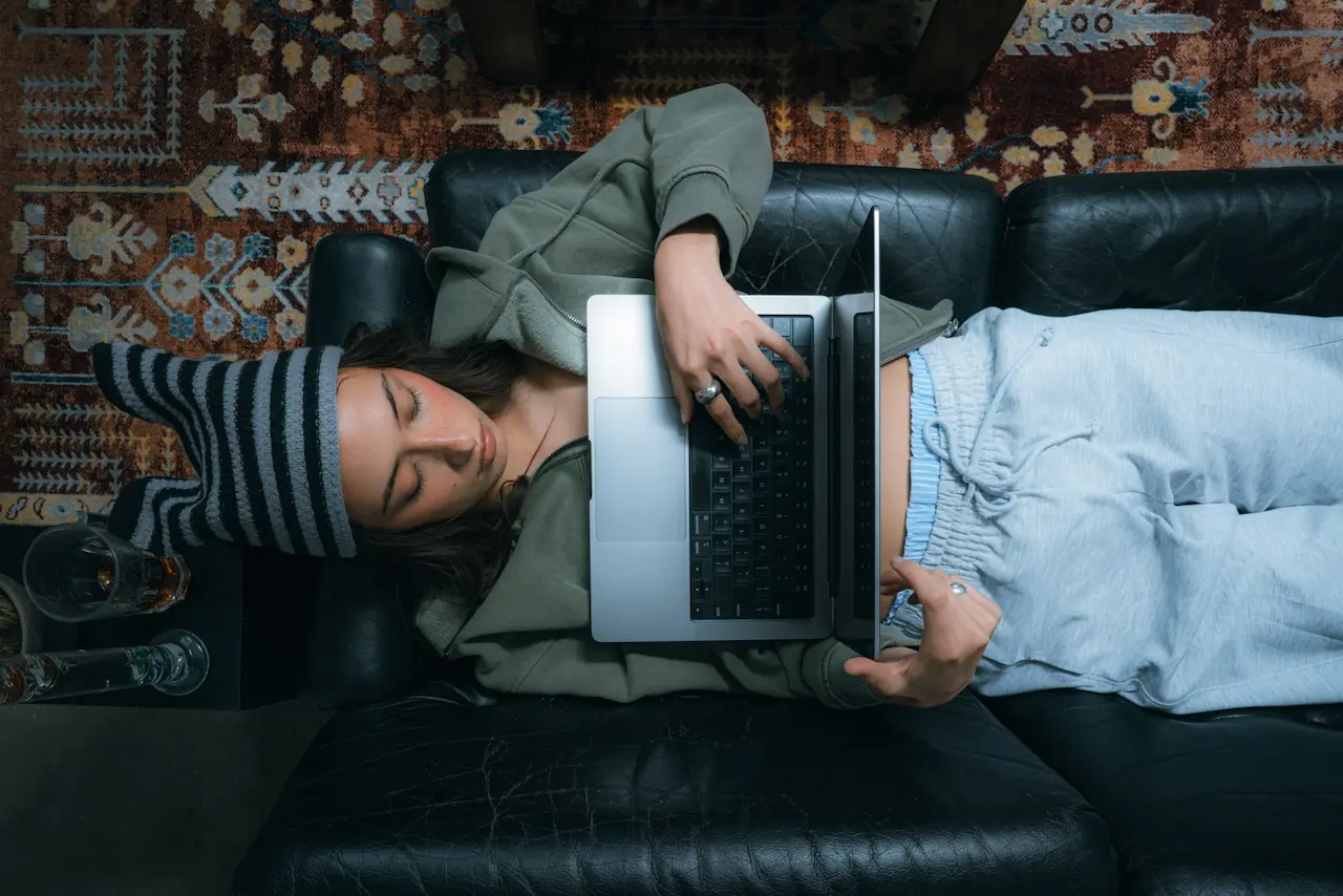 Someone lying on a couch with their laptop on their lap